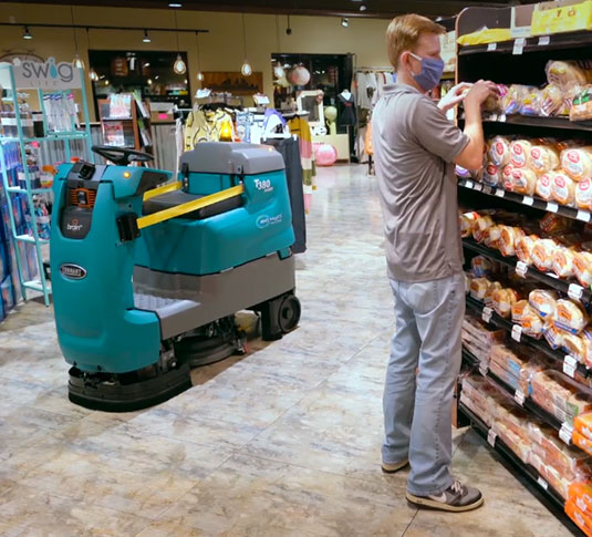 Tennant robotic floor scrubber cleaning aisle in grocery store