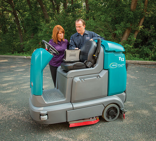 Tennant Service Representative with customer and T12 Ride-On Scrubber