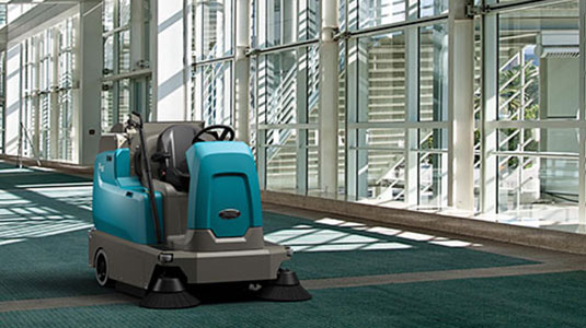 Tennant's new S16 ride-on carpet sweeper cleaning a convention center