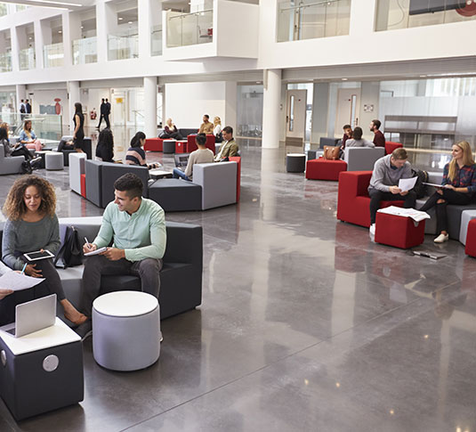 People work together in a public space. Sustainability initiatives can help increase attendance and satisfaction among a building’s occupants.